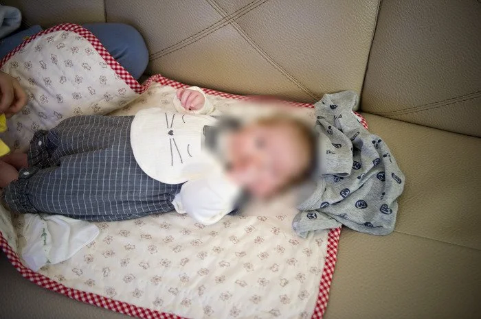 고양이 턱받이를 하고 담요 위에 누운 아기