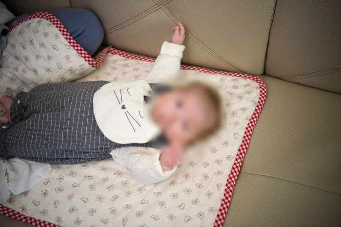고양이 턱받이를 하고 담요 위에 누운 아기