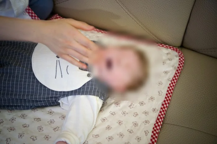 손으로 얼굴을 가리며 재채기하는 아기