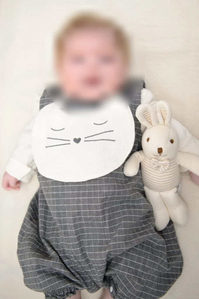 세로로 담은 토끼 인형 옆에 누운 아기