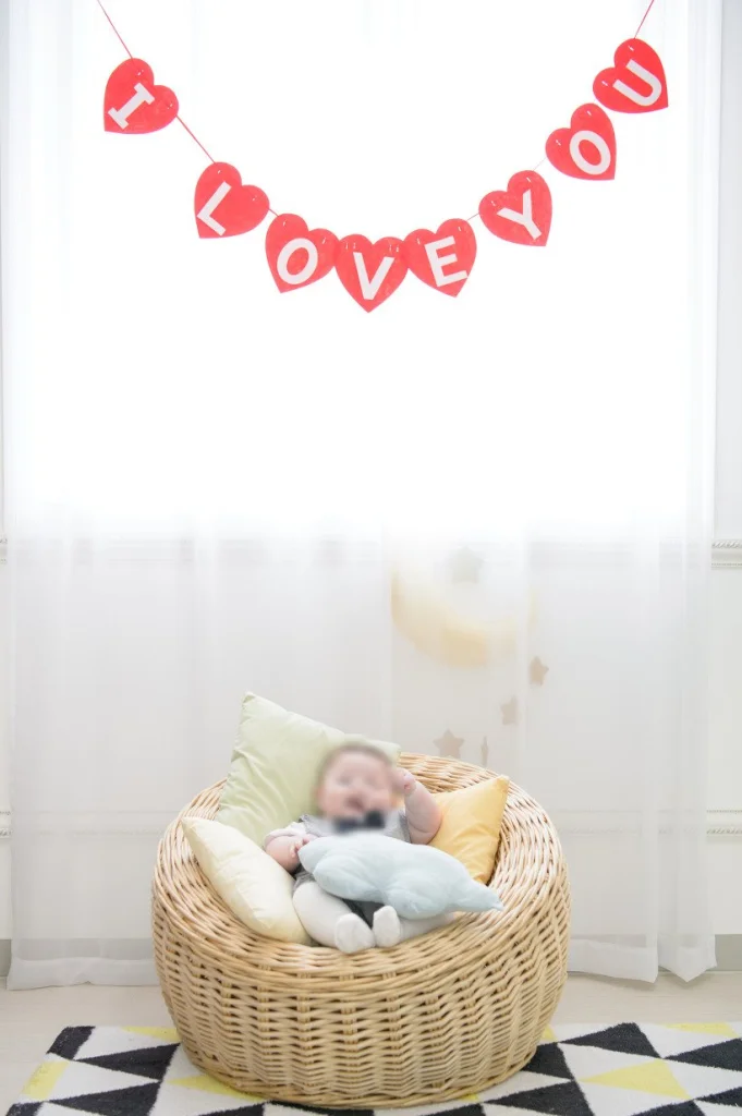 I LOVE YOU 가랜드 아래 라탄 의자에 앉은 아기