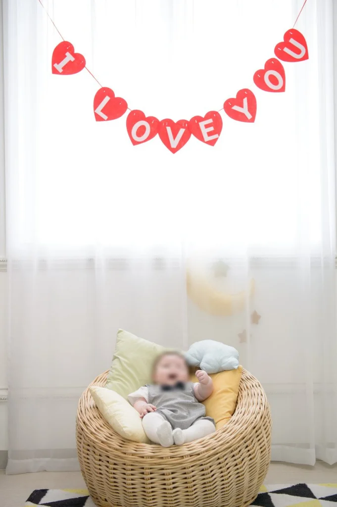 I LOVE YOU 가랜드 아래 라탄 의자에 앉은 아기
