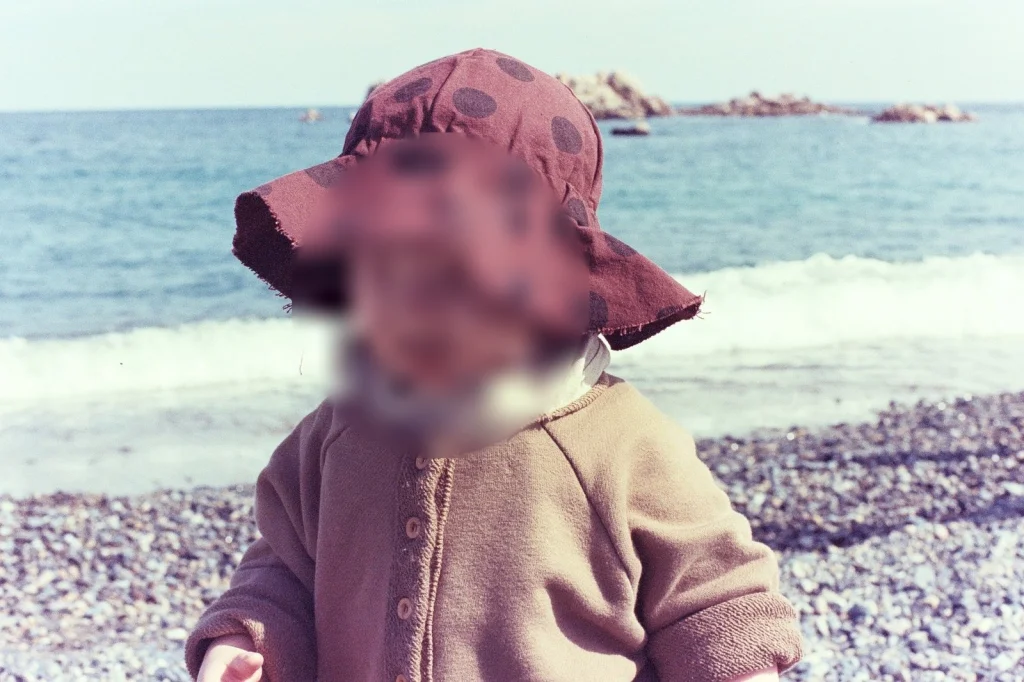 챙 넓은 모자를 쓰고 자갈 해변에 선 아들