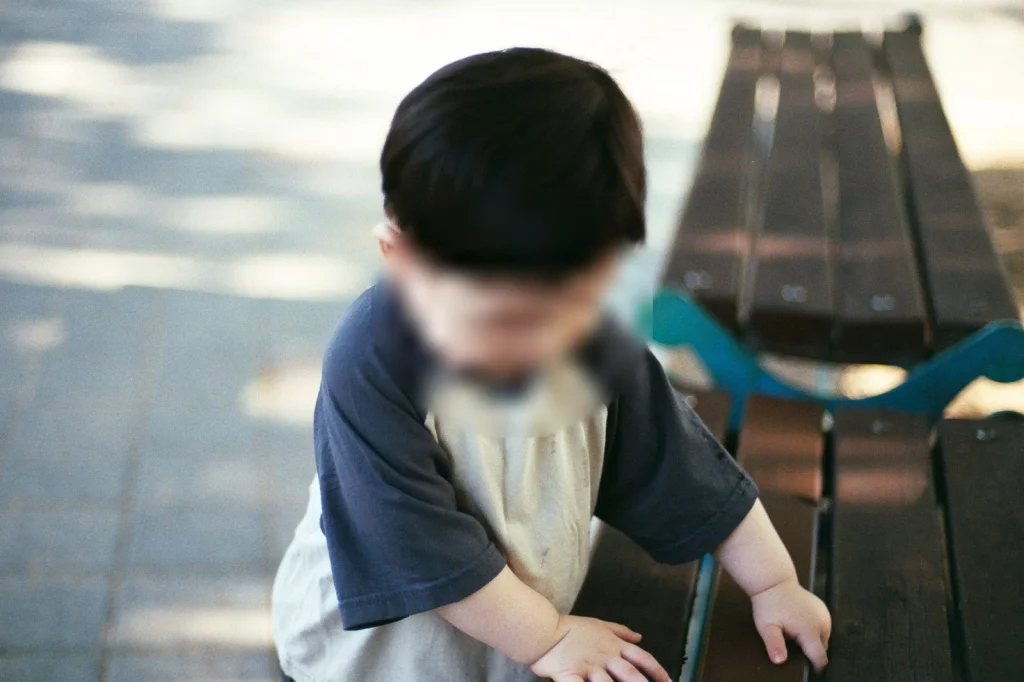 나무 벤치를 짚고 선 아들