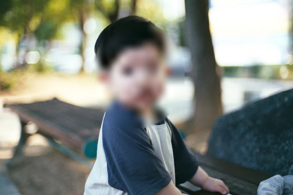 나무 그늘 벤치 옆에 선 아들