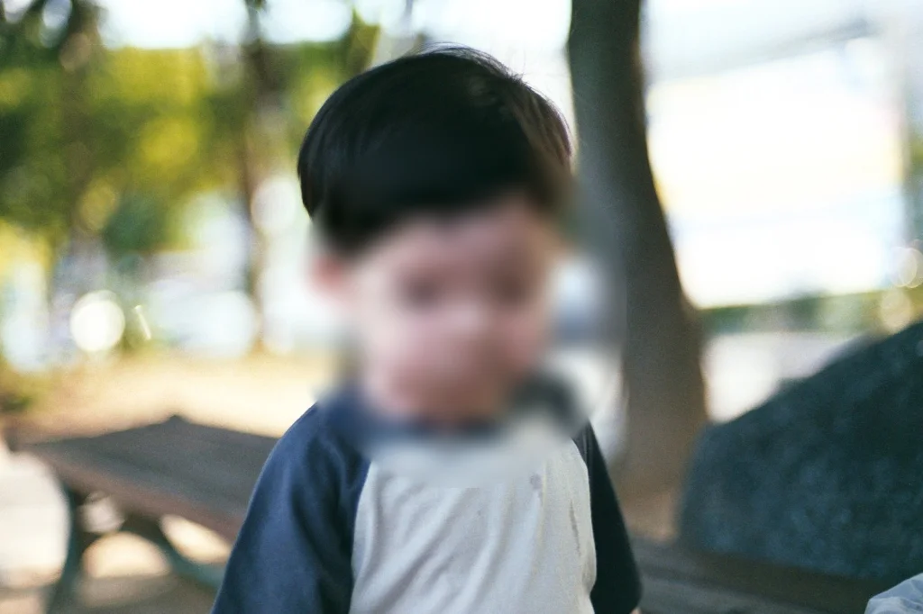 나무 그늘 벤치 옆에 선 아들