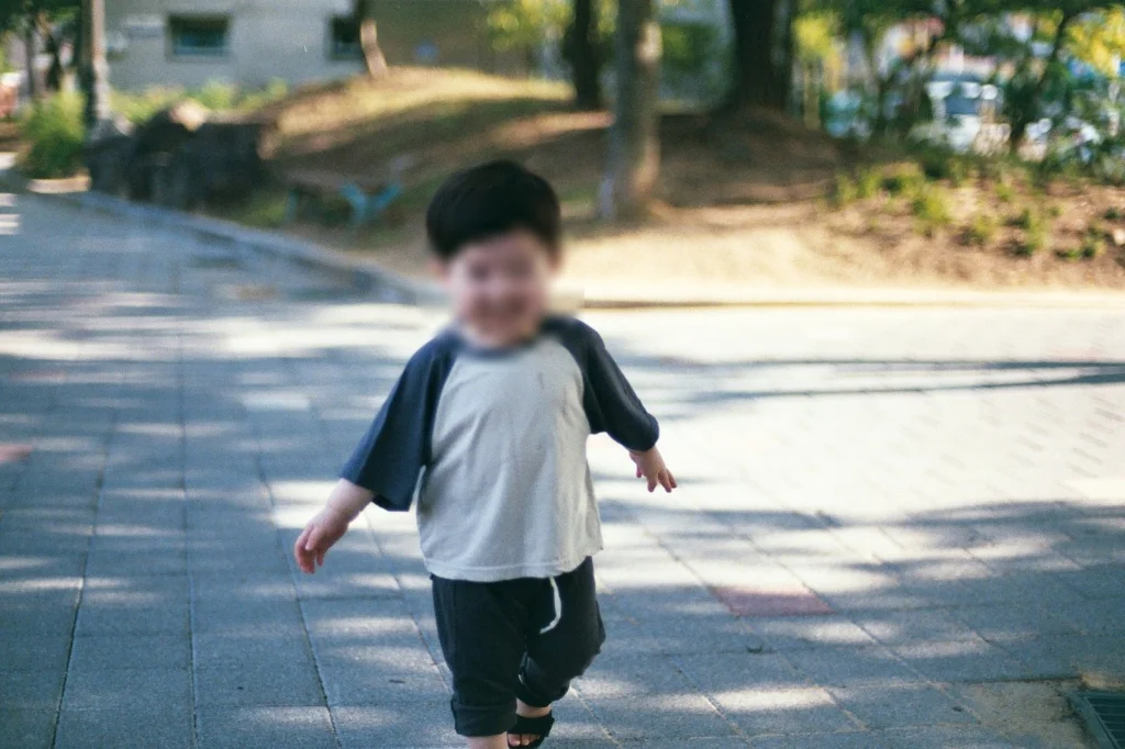 햇빛 드는 보도블록 길을 걸어오는 아들