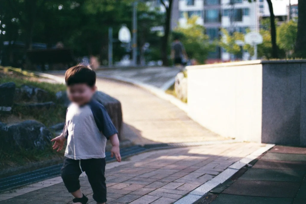 낮은 돌벽 앞 경사로를 걷는 아들