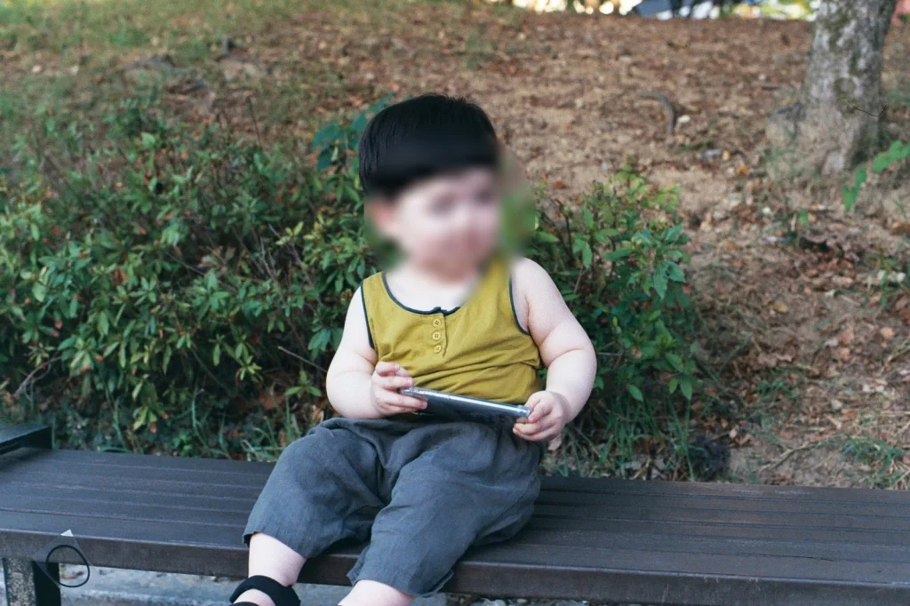 민소매 차림으로 나무 벤치에 앉은 아들