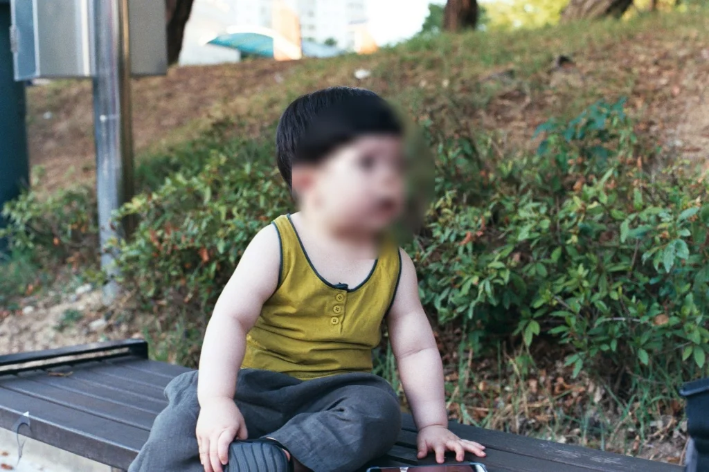 민소매 차림으로 나무 벤치에 앉은 아들