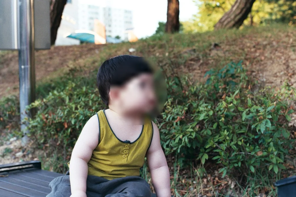 민소매 차림으로 나무 벤치에 앉은 아들