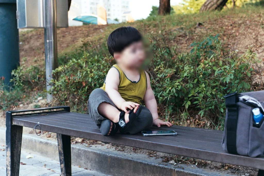 민소매 차림으로 나무 벤치에 앉은 아들