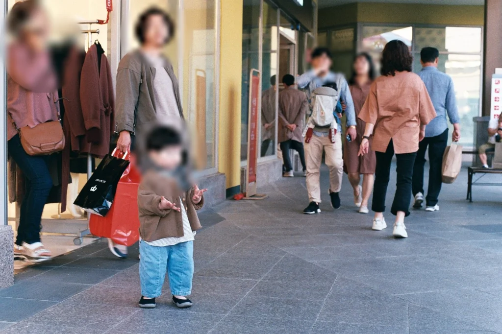 가게 앞에서 쇼핑백을 든 사람들 사이에 선 아들