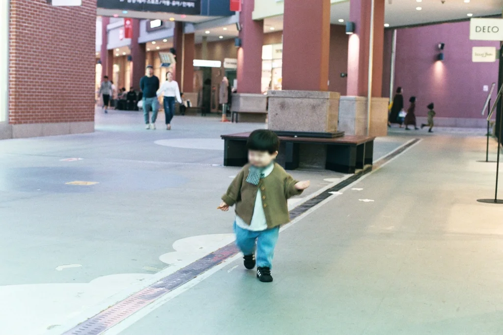 벽돌 기둥이 늘어선 쇼핑몰 통로를 걷는 아들