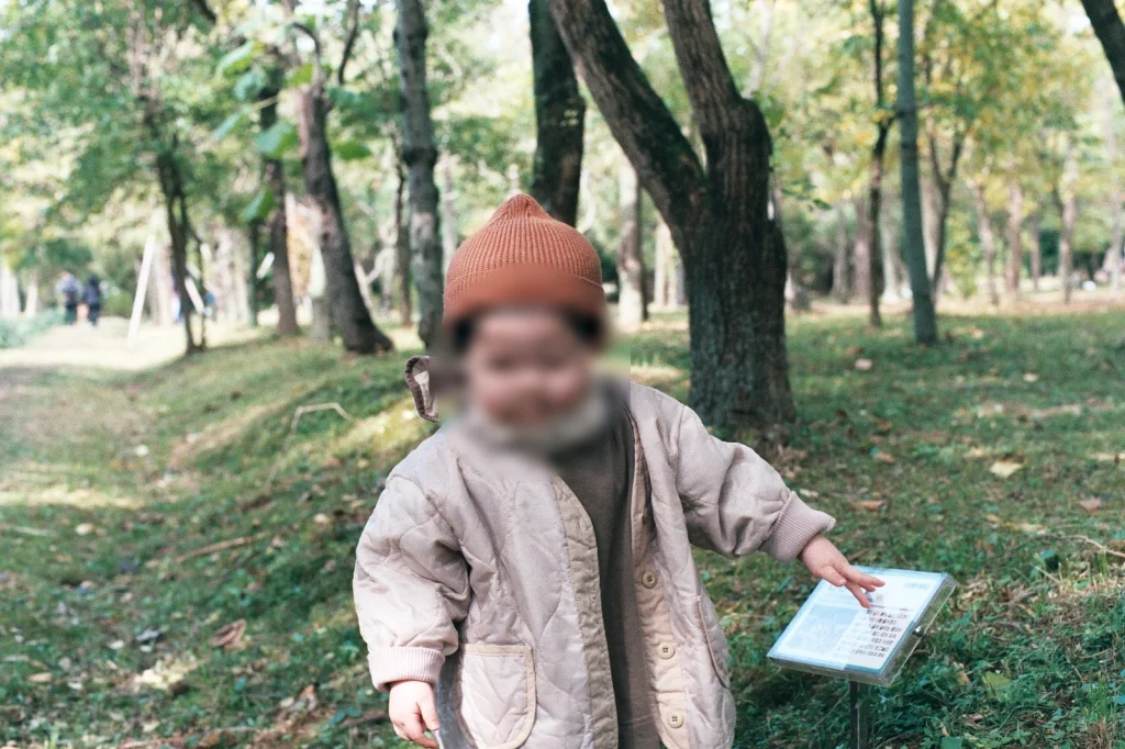 털모자를 쓰고 숲 속 안내판을 만지는 아들