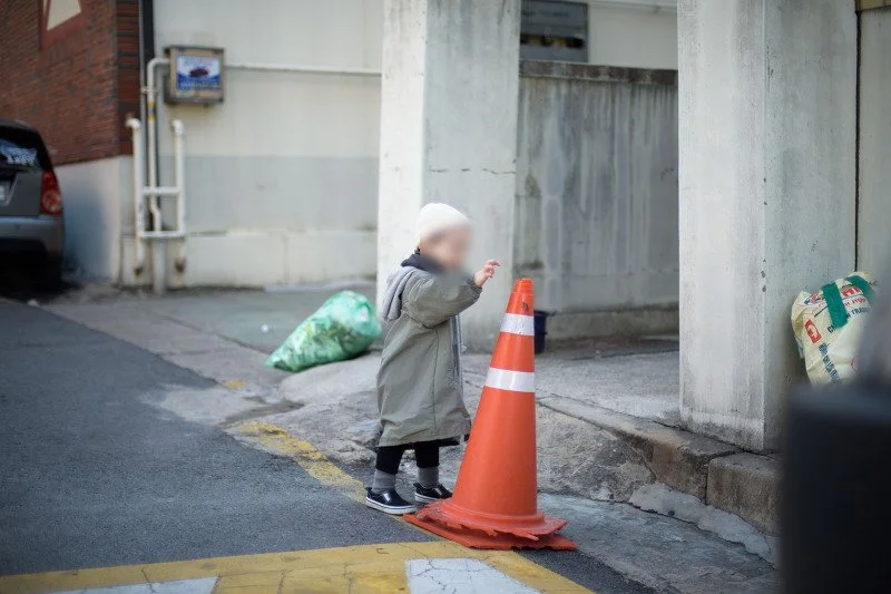 주황색 라바콘 옆 골목에서 노는 아들