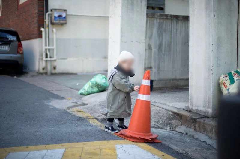 주황색 라바콘 옆 골목에서 노는 아들