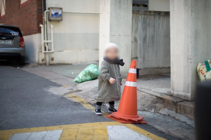 주황색 라바콘 옆 골목에서 노는 아들