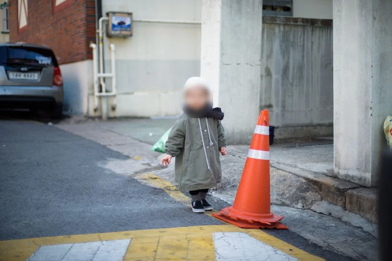 주황색 라바콘 옆 골목에서 노는 아들
