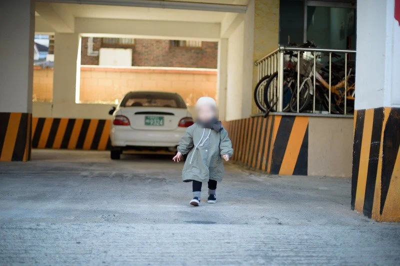 주차장 기둥 사이를 걸어 나오는 아들