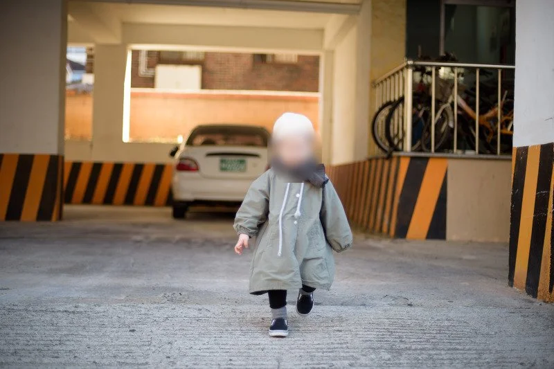 주차장 기둥 사이를 걸어 나오는 아들