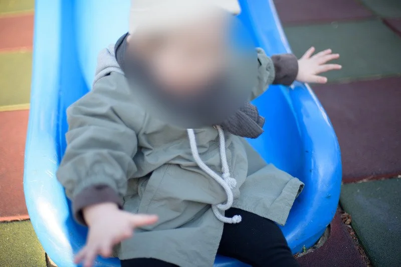 미끄럼틀 끝에서 몸이 앞으로 쏠린 아들