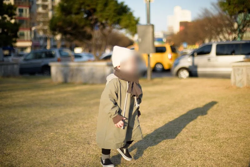 마른 잔디밭 위를 긴 그림자와 함께 달리는 아들
