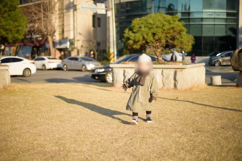 마른 잔디밭 위를 긴 그림자와 함께 달리는 아들