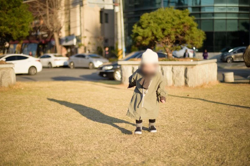 마른 잔디밭 위를 긴 그림자와 함께 달리는 아들