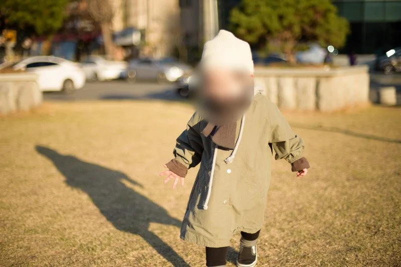 마른 잔디밭 위를 긴 그림자와 함께 달리는 아들