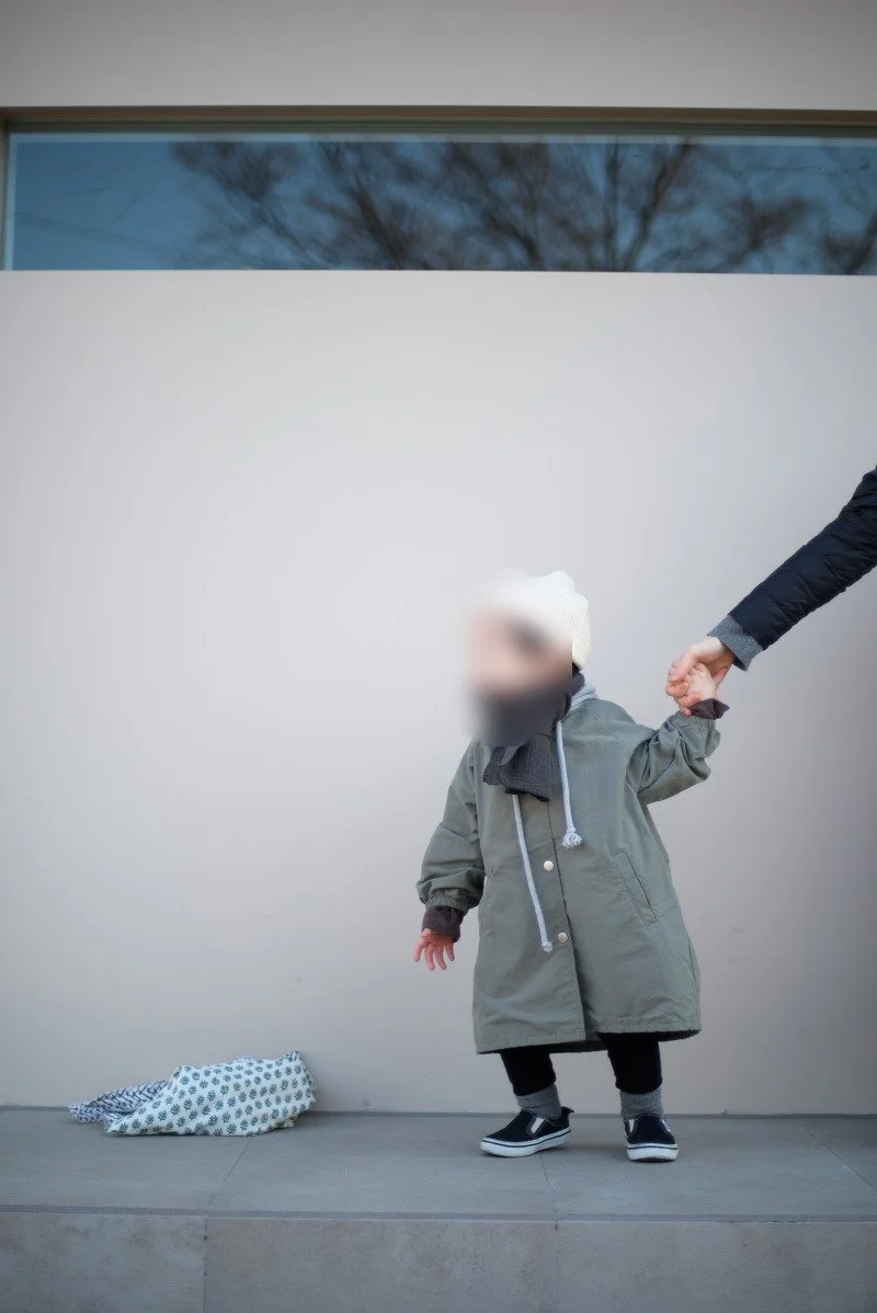 흰 벽 앞 턱 위에서 손을 잡고 선 아들