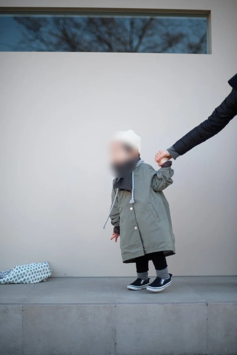 흰 벽 앞 턱 위에서 손을 잡고 선 아들