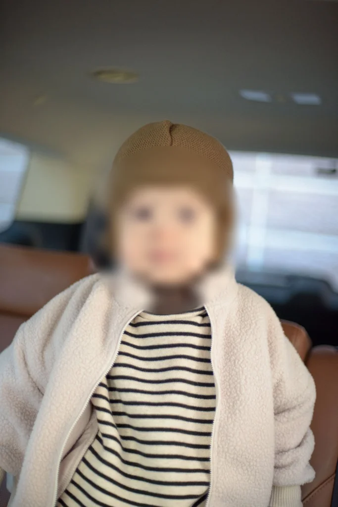 털모자를 쓰고 차 안에 앉아 웃는 아들