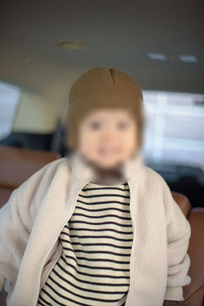 털모자를 쓰고 차 안에 앉아 웃는 아들