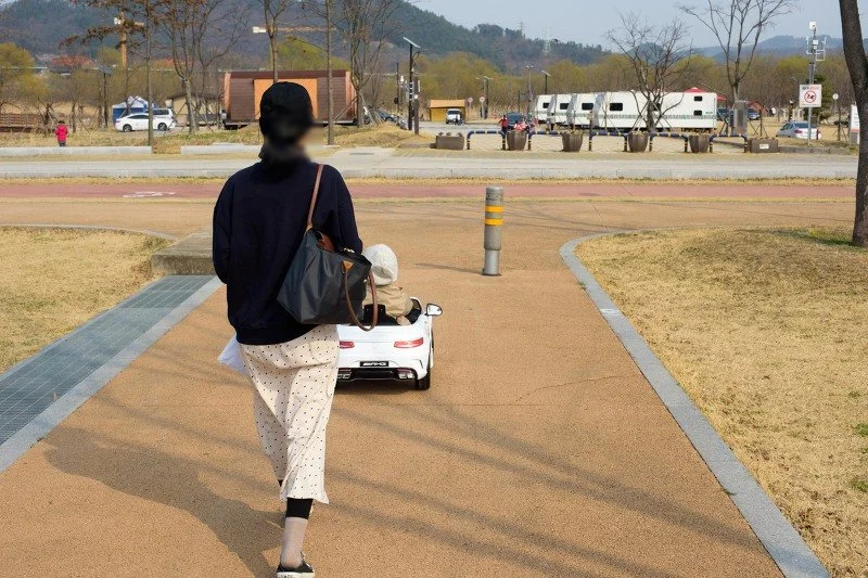 전동 자동차를 뒤따라 산책로를 걷는 아내