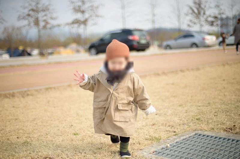 목도리를 두르고 잔디밭을 달리며 웃는 아들