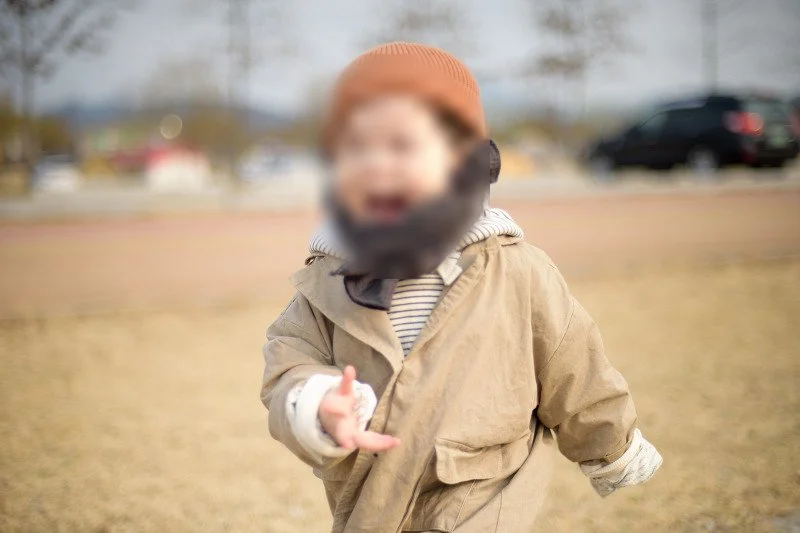 목도리를 두르고 잔디밭을 달리며 웃는 아들