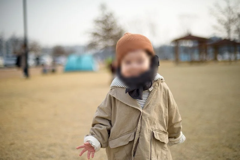 공원 잔디밭에서 웃는 털모자 쓴 아들