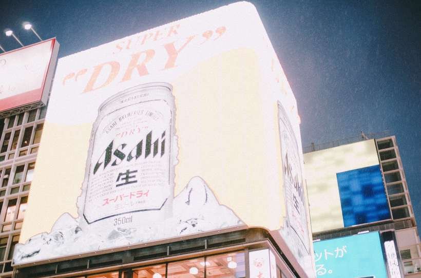 비 오는 밤하늘 아래 건물 위의 대형 맥주 광고판