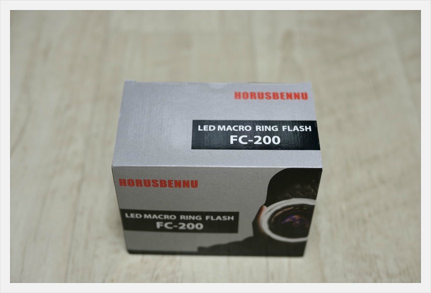 은회색 호루스벤누 FC-200 LED 링플래시 상자를 밝은 나무 무늬 바닥에 올려 둔 모습