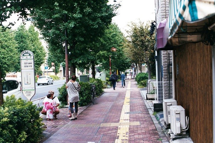 가로수가 선 보도와 버스 정류장 표지