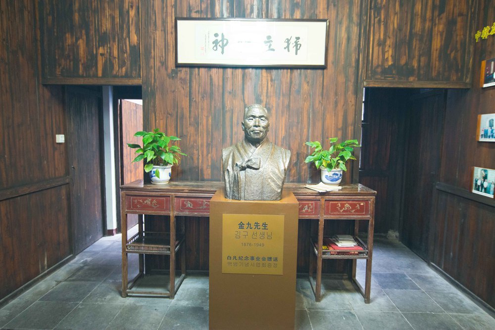 나무 벽 앞 청동 흉상과 받침대, 받침대 명판에 金九先生과 김구 선생님이 적혀 있다