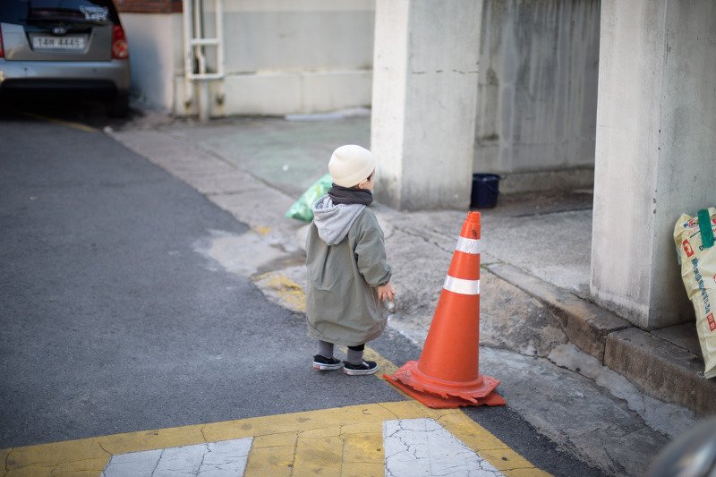 주황색 라바콘 옆 골목에서 노는 아들