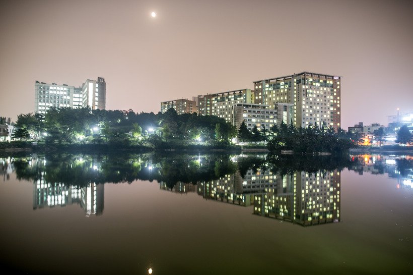밤의 일감호. 하늘 왼쪽 위에 달이 떠 있고 불이 켜진 고층 건물이 잔잔한 수면에 그대로 비친다