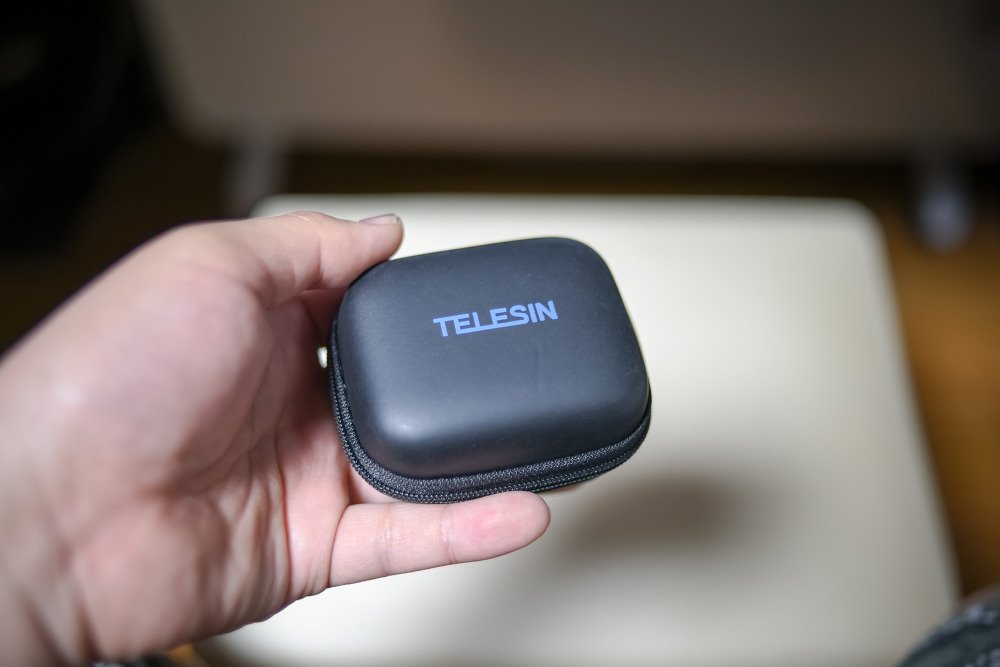 손바닥 위에 올린 TELESIN 로고가 있는 작은 검은 지퍼 케이스