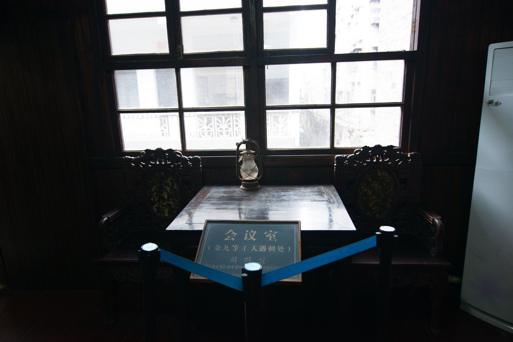 어두운 방의 탁자 앞 명판, 한자 会议室와 한글 회의실이 적혀 있고 파란 줄이 쳐져 있다