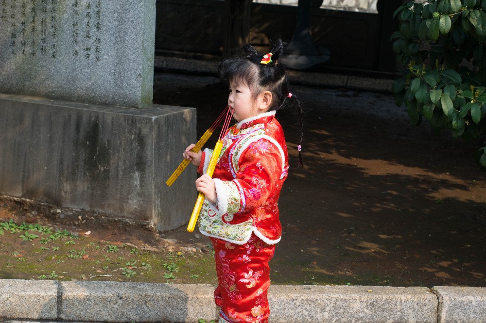 비석 옆에 선 붉은 옷의 아이