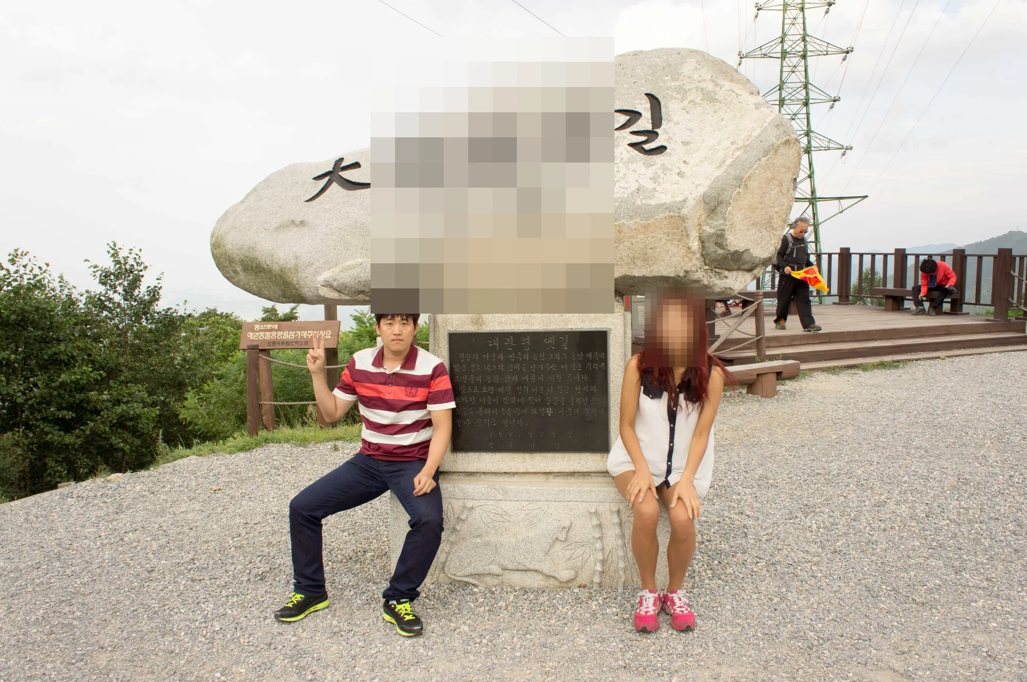 표지석 앞에 나란히 앉은 친구들