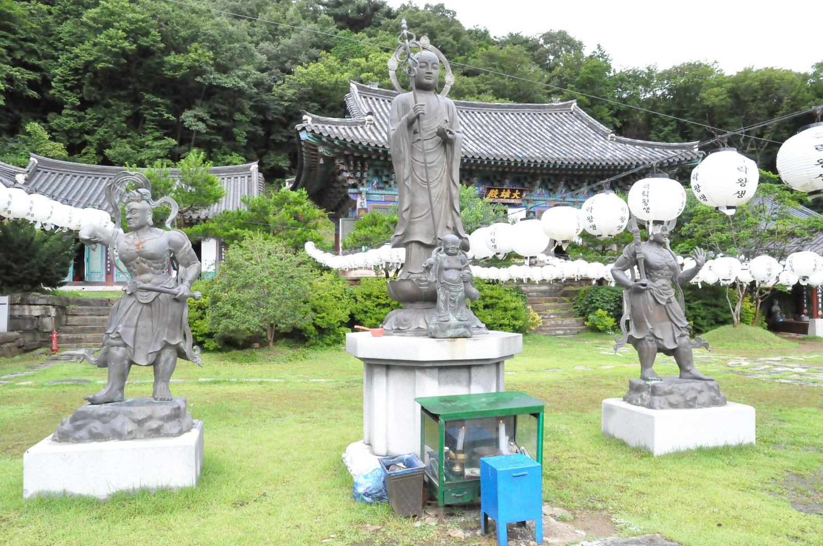단청 전각을 배경으로 나란히 선 청동 사천왕상 두 기
