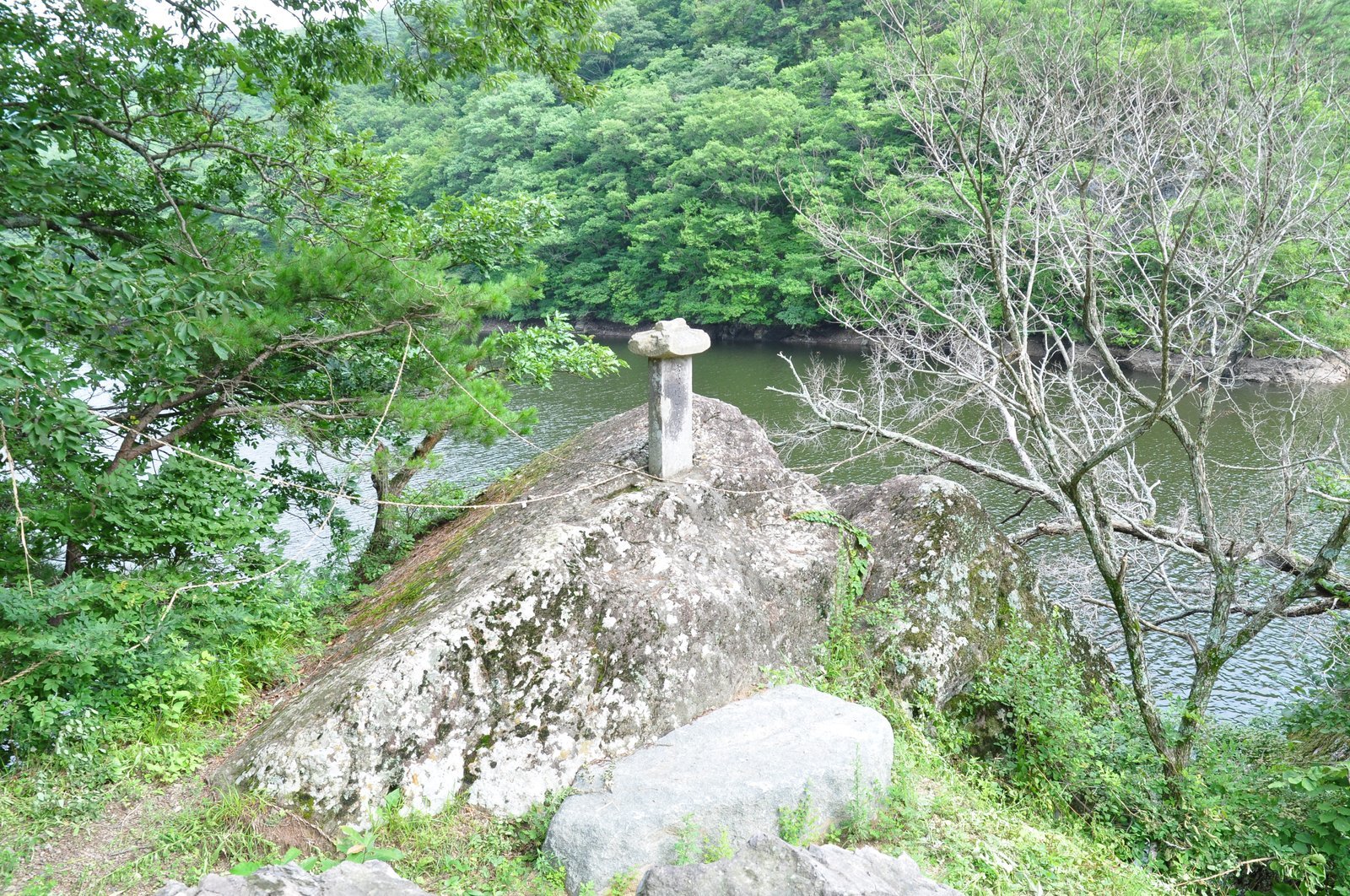 바위 위에 선 작은 돌기둥과 저수지